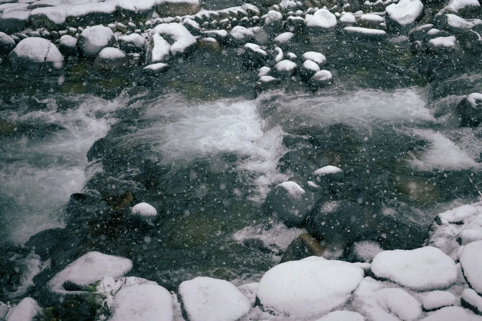 雪が降る中で流れる川